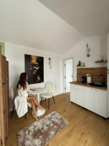 a woman sitting on a chair in a kitchen at Veya Cabins Apuseni in Trifeşti