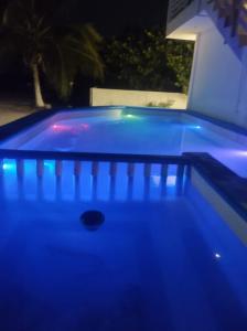 a pool with blue lights in a backyard at night at Posada "Las Palmeras" in Dzilam de Bravo