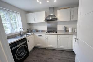 a kitchen with white cabinets and a washer at Rudge House in Lichfield