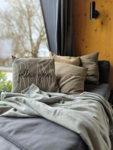 a bed with a blanket and pillows in a room at Tiny House 1 im schönen Allgäu mit großem Garten, Naturnah in Bad Wurzach