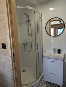 a bathroom with a shower and a sink and a mirror at Domki Słodka Magnolia in Karwia +8 photos