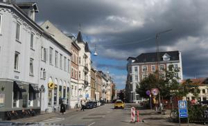 a city street with buildings and a yellow taxi at Greenbrook - Black Suite in Aalborg +9 photos