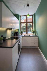 a kitchen with white cabinets and green walls at Greenbrook - Black Suite in Aalborg