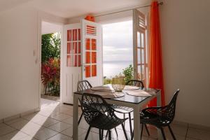 a dining room with a table and chairs and a window at Gîtes Dardanelle in Bouillante
