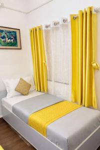a bedroom with two beds with yellow curtains at Elite Hostel- SB Road Pune in Pune