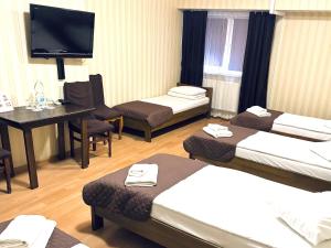 a hotel room with three beds and a desk and a television at Etna Hotel in Lviv