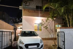 a white car parked in front of a building at Elite Hostel- SB Road Pune in Pune