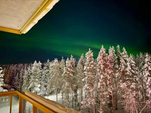 an image of a forest of trees with the aurora in the sky at Levi City Suite - Central & Stylish with Free Ski Passes in Levi