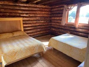 a bedroom with two beds in a log cabin at Mexiquillo - La Fogata - Cabin #5 in La Ciudad