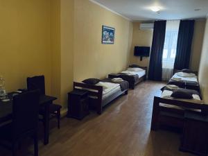 a room with three beds and a table and chairs at Etna Hotel in Lviv