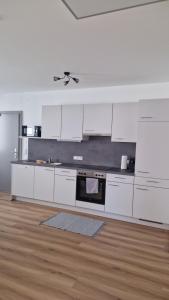 a white kitchen with white cabinets and a stove at Appartements Stadler in Breitenbrunn +4 photos