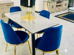 a table with four blue chairs and a vase on top at 7th Heaven luxury Apartment in Gaborone