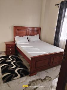 a bed in a bedroom with a wooden bed frame and a rug at Luxury Homes in Mtwapa