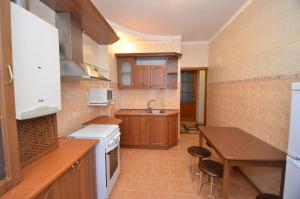 una cocina con armarios de madera, mesa y fregadero en Apartment in the center on Spasskaya Street, en Mykolaiv