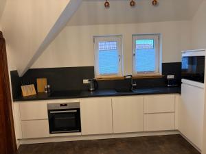 a kitchen with white cabinets and a sink and two windows at Business Apartment in Paderborn +4 photos