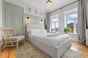 a white bedroom with a bed and a chair at Stunning Townhouse - 7 bedrooms - up to 18 Guests in Cardiff