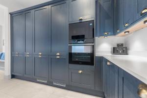 a kitchen with navy blue cabinets and appliances at Stunning Townhouse - 7 bedrooms - up to 18 Guests in Cardiff