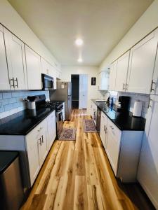 a kitchen with white cabinets and a wooden floor at The Willowdell Nook in Mulvane +11 photos