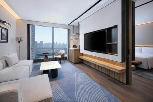 a living room with a flat screen tv and a bed at Sheraton Ningbo Yinzhou in Ningbo