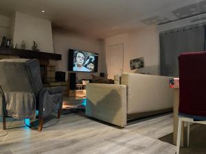 a living room with a couch and a flat screen tv at Maison de Campagne in Aussonne