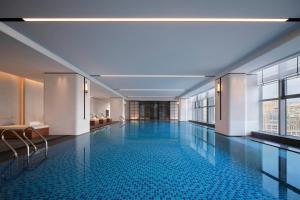 a large swimming pool in a building with windows at Sheraton Ningbo Yinzhou in Ningbo