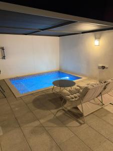 a swimming pool with a table and a chair in a room at ستاي إن Stay Inn in Ma‘mad
