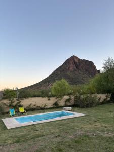 a pool with two chairs and a mountain in the background at Cabaña La Verdicchio Privacidad y exclusividad Tu lugar de descanso in Valle Grande