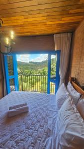 a bedroom with a large bed with a large window at Chalés Monte das Oliveiras in Domingos Martins +179 photos