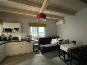 a kitchen and a living room with a couch and a table at Domek pod lasem in Pogorzelica