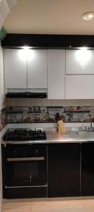 a kitchen with a black stove and white cabinets at La Pradera in Pereira +24 photos