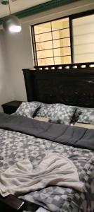 an unmade bed in a bedroom with two windows at La Pradera in Pereira