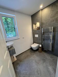 a bathroom with a toilet and a sink and a window at Holiday by Chelly in Zeitz