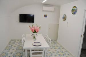 a white table and chairs with a vase of flowers on it at Casa Bianca Amalfi New Central Apt in Amalfi