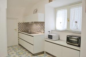 a kitchen with white cabinets and a microwave at Casa Bianca Amalfi New Central Apt in Amalfi