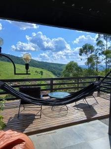 a hammock on a deck with a view of a field at Casa com piscina aquecida, estilosa e privativa in Nazaré Paulista