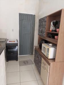 a small kitchen with a microwave and a door at Casa mobiliada 2 Com 4 camas e 2 quartos com ar condicionado in Juazeiro do Norte