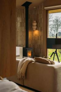 a living room with a fireplace with a couch and a window at Gastenverblijf Buitenhoudt in Vinkel