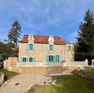 a large stone house with blue shutters and a fence at Le Petit Manoir avec Piscine Privée in Le Bugue
