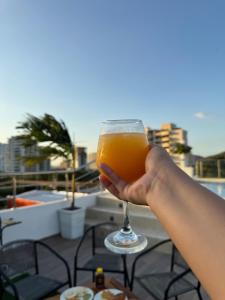 a person holding up a glass of orange juice at Hotel Bello Horizonte in Santa Marta