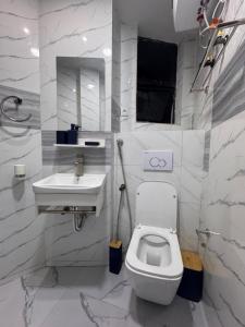 a white bathroom with a toilet and a sink at Chez Charly in Kinshasa