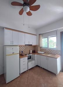 a kitchen with white cabinets and a ceiling fan at O&A Kallithea in Kallithea Halkidikis