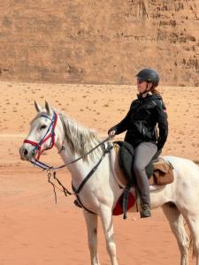 a woman riding a white horse in the desert at Wadi Rum Desert Experience in Wadi Rum