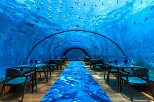 an underwater restaurant with tables and chairs under the water at Hurawalhi Island Resort in Kuredu