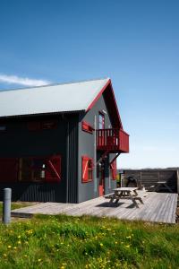 a black building with red windows and a wooden deck at Laugarfell Accommodation & Hot Springs in Laugarfell