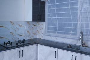 a kitchen with white cabinets and a sink and a window at Zubi Guest House in Dargai