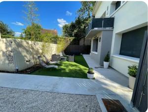 a small backyard with a lawn and a house at Chambre Attrape rêves in Sainte-Geneviève-des-Bois +4 photos