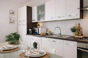 a kitchen with white cabinets and a sink and a dishwasher at SicilyNice in Avola