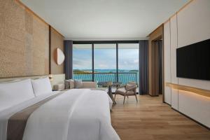 a hotel room with a large bed and a television at The Westin Nirup Island Resort & Spa in Belakangpandang