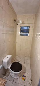 a bathroom with a toilet with a black seat at Meu Aconchego in Embu +17 photos