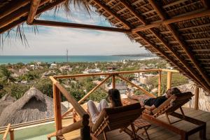 a group of three people sitting in chairs on a porch at Villa Macarena Apartamentos Boutique - Only Adults in Puerto Escondido